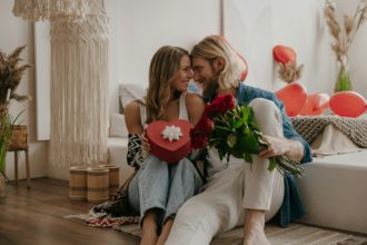 Loving couple embracing and holding roses and gift box