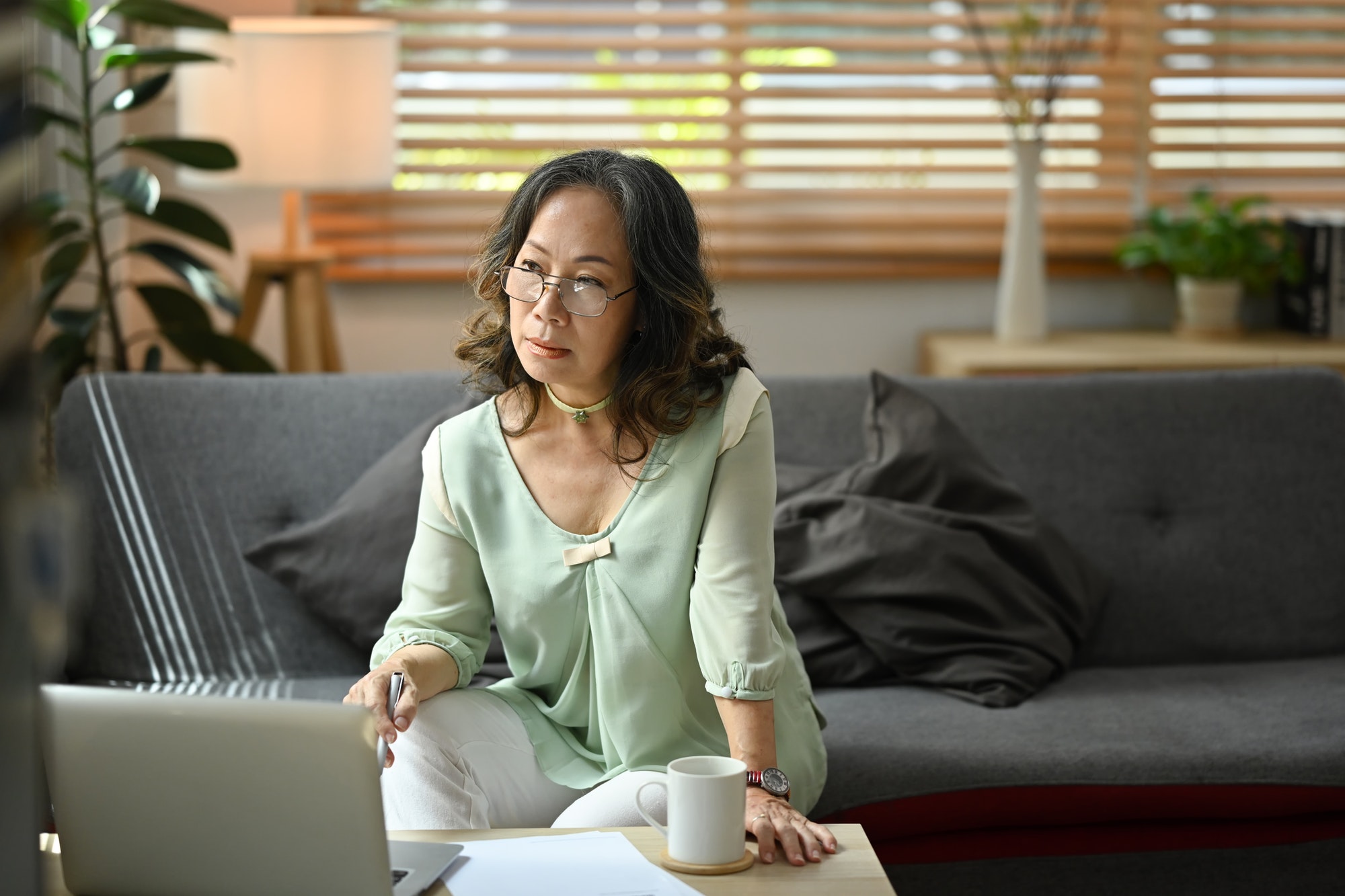 Mature woman reading news online, checking social media on laptop computer.