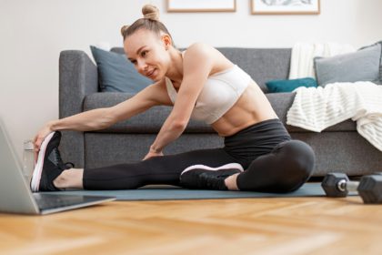 Sportswoman stretching during online training at home